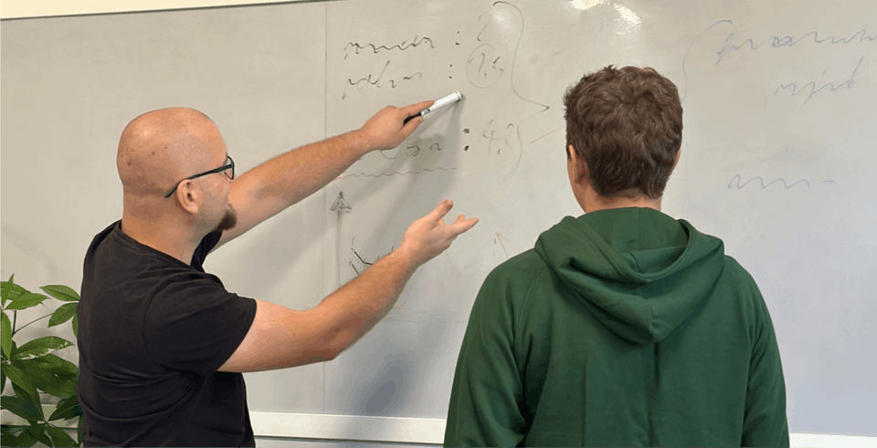 A photo showing two men standing in front of a whiteboard, discussing accessibility